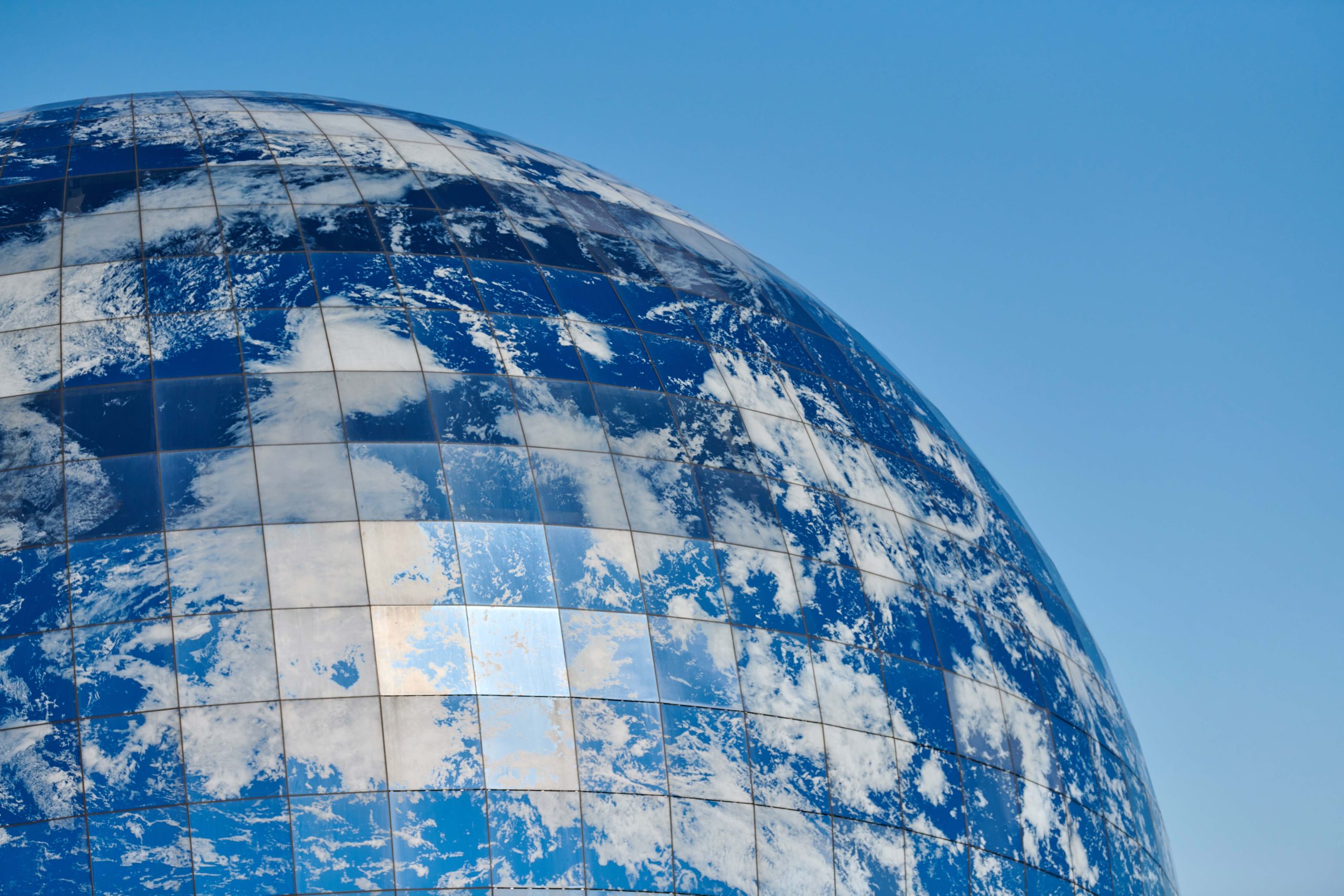 Earth planet modern building with clouds and blue sky, ecological architectural concept. Beautiful spherical facade of world ocean museum in Kaliningrad city, Russia, architectural globe exterior